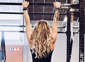 Woman with dark blonde wavy hair working out in the gym